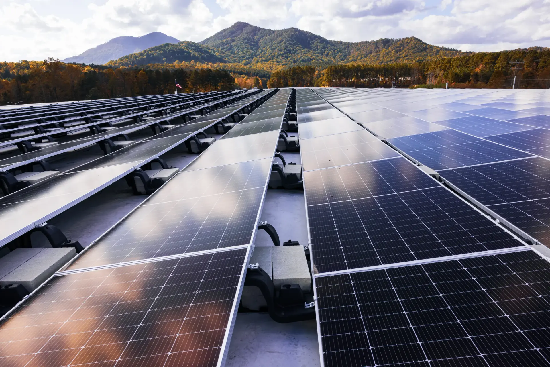 Commercial rooftop solar array on a Sollega ballasted racking system stretching toward a mountain horizon